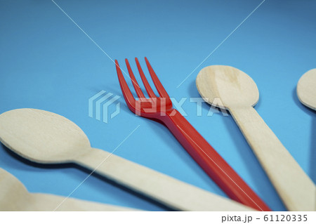 Single red plastic fork amongst wooden spoons Single red plastic fork amongst wooden spoons 61120335
