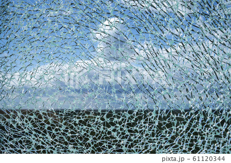 Cracked glass surface against blue sky 61120344