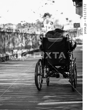 Picture of lonely old woman sitting on the wheelchair while looking at sunlight. Picture of lonely old woman sitting on the wheelchair while looking at sunlight. 61127272