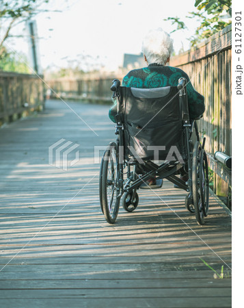 Picture of lonely old woman sitting on the wheelchair while looking at sunlight. Picture of lonely old woman sitting on the wheelchair while looking at sunlight. 61127301