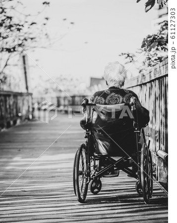 Picture of lonely old woman sitting on the wheelchair while looking at sunlight. 61127303