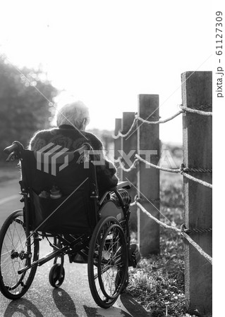 Picture of lonely old woman sitting on the wheelchair while looking at sunlight. Picture of lonely old woman sitting on the wheelchair while looking at sunlight. 61127309
