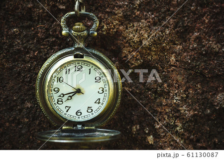 Vintage old pocket watch hanged on the rock background. At 8 o'clock. Closeup and copy space. 61130087