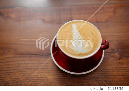Cappuccino in red cup on a wooden table overview. Cappuccino in red cup on a wooden table overview. 61133564
