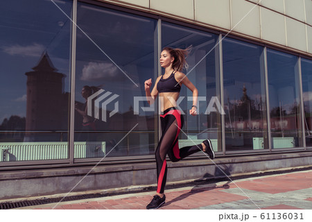 Beautiful dynamic sporty girl runs on jog in morning, lifestyle motivation in summer in city. Sportswear leggings top sneakers, tanned figure. Free space for copy text. Woman motion in jump. Beautiful dynamic sporty girl runs on jog in morning, lifestyle motivation in summer in city. Sportswear leggings top sneakers, tanned figure. Free space for copy text. Woman motion in jump. 61136031