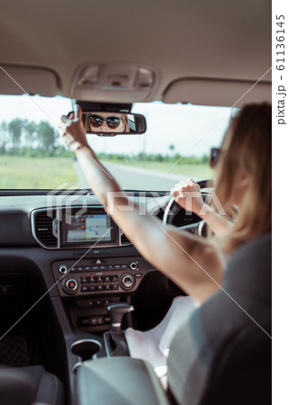 A woman driving a car, looking in the rearview mirror, reversing, parking at a shopping center, driving a car into the garage. Automatic transmission. Vehicle interior. Summer girl in a dress. 61136145