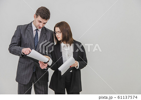 Successful businesspartners standing, holding clipboards, flipping over pages, looking through the documents, discussing important issues. Successful businesspartners standing, holding clipboards, flipping over pages, looking through the documents, discussing important issues. 61137574