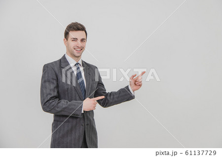 Successful handsome businessman standing, presenting a project, pointing his fingers at the copyspace for text or product. 61137729