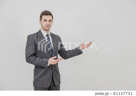 Successful handsome businessman standing, presenting a project, pointing his hands at the copyspace for text or product. Successful handsome businessman standing, presenting a project, pointing his hands at the copyspace for text or product. 61137731