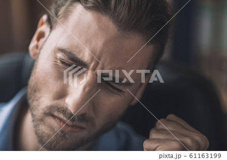 Young bearded man in blue shirt feeling headache Young bearded man in blue shirt feeling headache 61163199