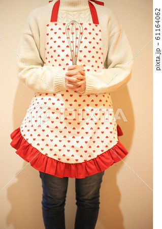 泡立て器を持ったエプロンの女性 61164062