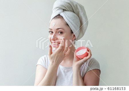 Minimal beauty woman girl in towel on head portrait applying white nourishing mask or creme on face isolated on white background. Skincare cleansing eco organic cosmetic spa concept. 61168153