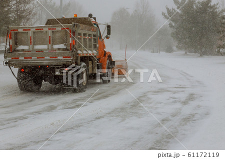 The snow-removing car cleans the road on heavy The snow-removing car cleans the road on heavy 61172119