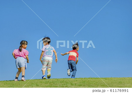 公園の丘で遊ぶ子供たちの後ろ姿の写真素材