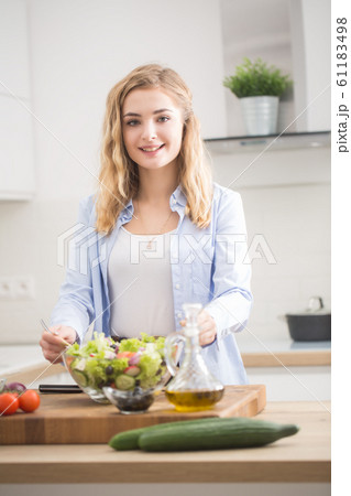 Young happy blonde girl preparing healthy salad in Young happy blonde girl preparing healthy salad in 61183498