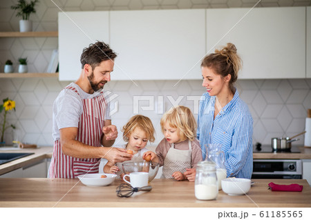Young family with two small children indoors in kitchen, cooking. 61185565