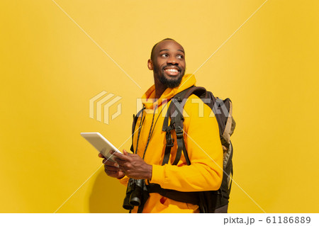 Full length portrait of a cheerful young african tourist guy isolated on yellow background Full length portrait of a cheerful young african tourist guy isolated on yellow background 61186889
