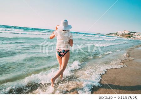 Young Caucasian Lady Woman In Summer Hat Runs Along The Seashore Sea Beach. Vacation On Sea Ocean Beach Young Caucasian Lady Woman In Summer Hat Runs Along The Seashore Sea Beach. Vacation On Sea Ocean Beach 61187650