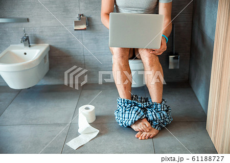 Young man using modern notebook in toilet Young man using modern notebook in toilet 61188727