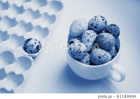 Quail eggs in cup and cardboard packaging on blue Quail eggs in cup and cardboard packaging on blue 61189884