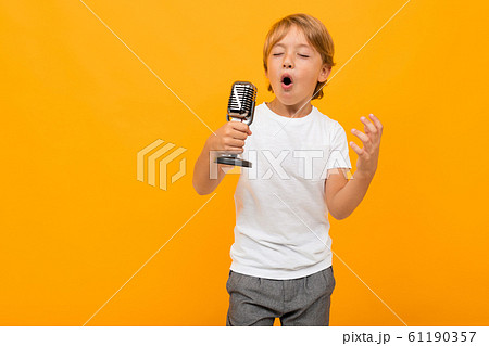 blond boy with a microphone on an orange background 61190357