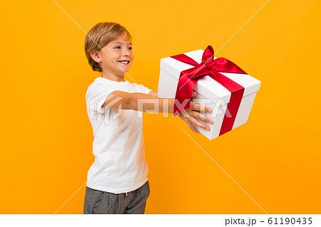 valentine's day concept. attractive boy holds out a box with a gift with a red ribbon on a bright valentine's day concept. attractive boy holds out a box with a gift with a red ribbon on a bright 61190435