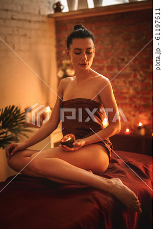 Alternative Medicine. Woman sitting in towel holding aroma candle Alternative Medicine. Woman sitting in towel holding aroma candle 61197611