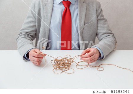 Alone businessman try to unwinds tangled thread ball like puzzle out situation. Conceptual photo. Alone businessman try to unwinds tangled thread ball like puzzle out situation. Conceptual photo. 61198545