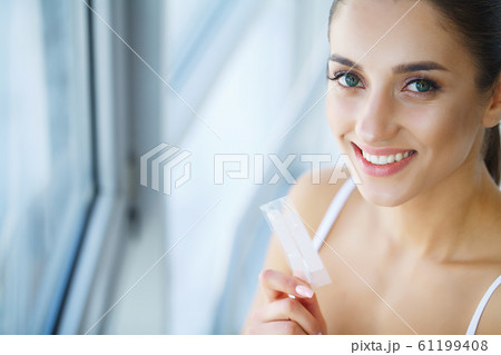 Teeth Whitening. Beautiful Smiling Woman Holding Whitening Strip. High Resolution Image 61199408