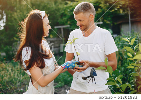 Beautiful couple works in a garden near the house Beautiful couple works in a garden near the house 61201933