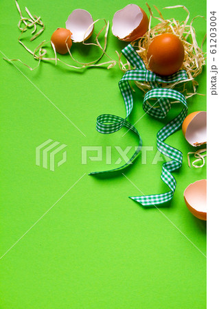 Brown chicken egg in a straw nest, broken eggshell 61203004