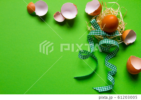 Brown chicken egg in a straw nest, broken eggshell 61203005