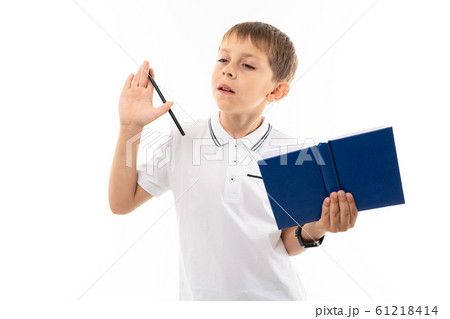 European boy thinks with a book and pen in his hands on a white background 61218414
