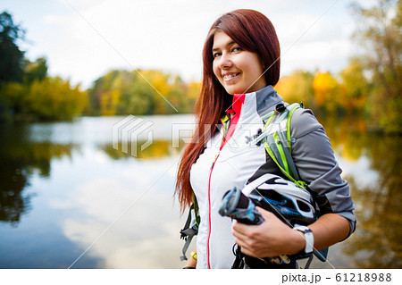 Picture of smiling woman with backpack and bicycle helmet 61218988