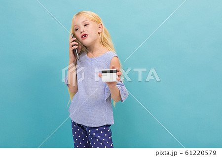 Portrait of little caucasian girl in blue t-shirt with long blonde hair holds a credit card isolated Portrait of little caucasian girl in blue t-shirt with long blonde hair holds a credit card isolated 61220579