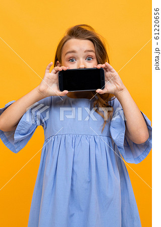 vertical portrait of a girl with a phone in a horizontal position with a layout on a yellow 61220656