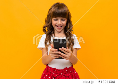 girl in a white T-shirt reads messages on the phone on an orange background 61221608