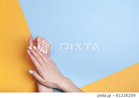 Beautiful female hands with a classic matte manicure on a blue-yellow background 61226209