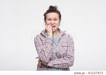 Frightened and stressed young student woman biting her fingers Frightened and stressed young student woman biting her fingers 61227872