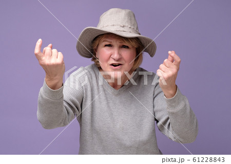 Mature woman in summer hat standing and looking at camera and screaming. Mature woman in summer hat standing and looking at camera and screaming. 61228843