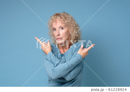 Mature blonde woman pointing to both sides with fingers in different direction 61228924