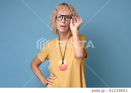 Mature caucasian woman with glasses looks attentively Mature caucasian woman with glasses looks attentively 61229001
