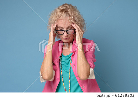 Mature caucasian woman in colored clothes touching her thead feeling stress Mature caucasian woman in colored clothes touching her thead feeling stress 61229202