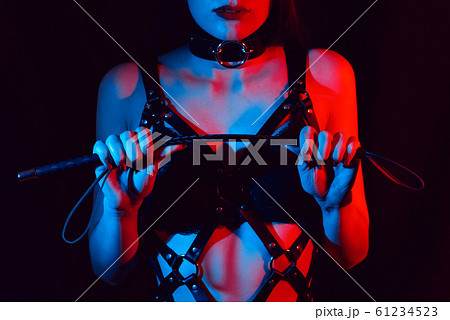 girl in a leather harness holds a Flogger whip in her hands 61234523