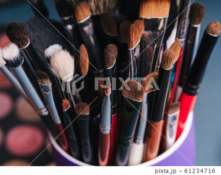 set of makeup brushes on the background of a professional palette with eye shadows set of makeup brushes on the background of a professional palette with eye shadows 61234716