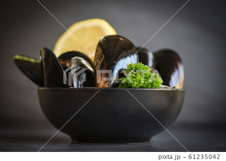 Raw Mussels with herbs lemon on bowl and dark Raw Mussels with herbs lemon on bowl and dark 61235042