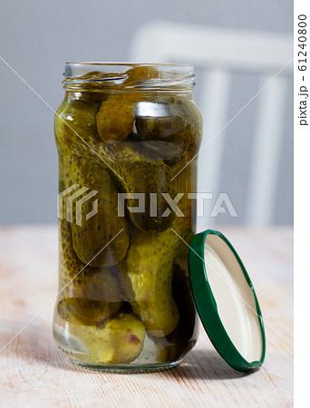 Glass jar with pickled cucumbers on a wooden table 61240800