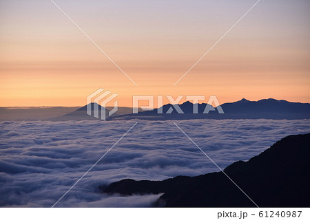 朝焼けの空に照らされて雲海に浮かぶ富士山と南アルプスのシルエット:北アルプスから 朝焼けの空に照らされて雲海に浮かぶ富士山と南アルプスのシルエット:北アルプスから 61240987