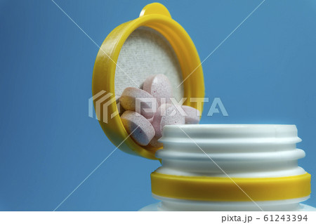 Medicine pills spilling out of a white bottle 61243394