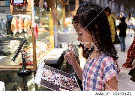 Asian cute girl ordering from menu at food court in mall 61245325